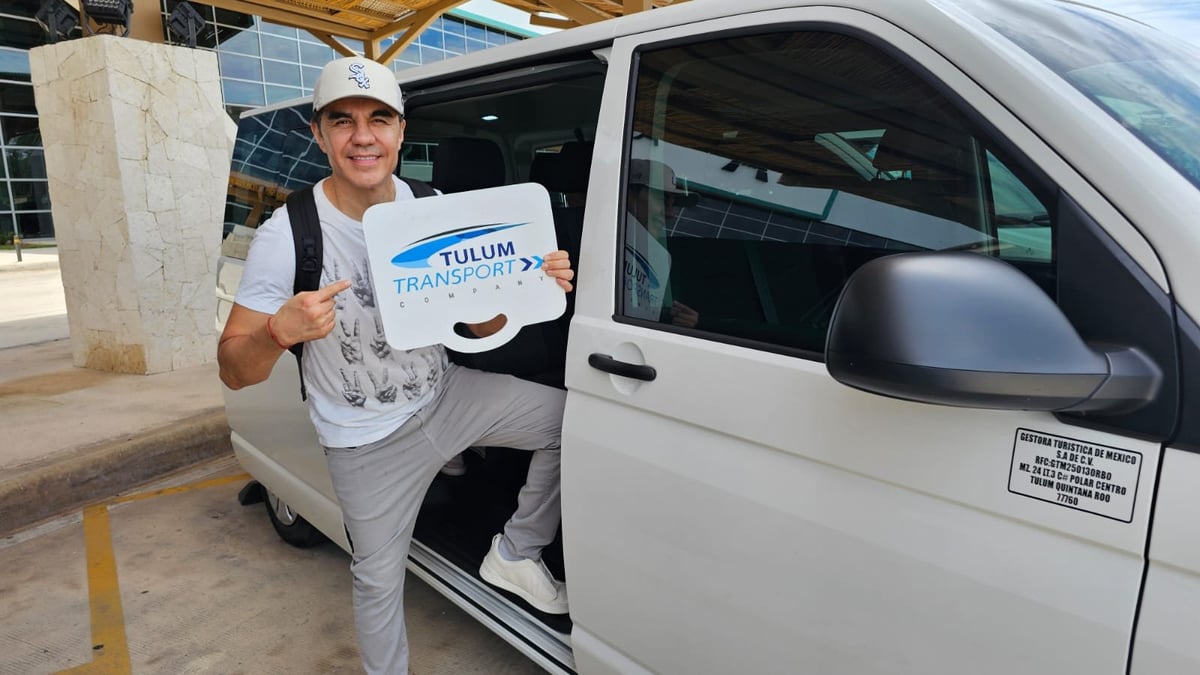 Adrian Uribe holding a Tulum Transport Company sign beside a private transfer van