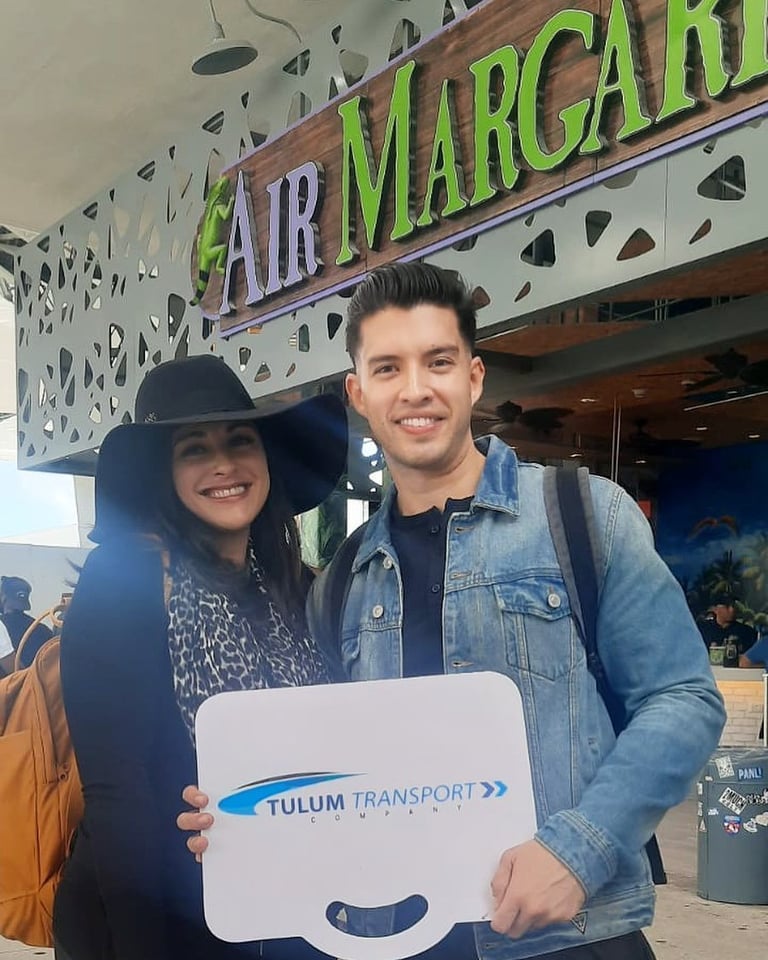 Two travelers holding a TTC welcome sign at the Cancun Airport meeting point